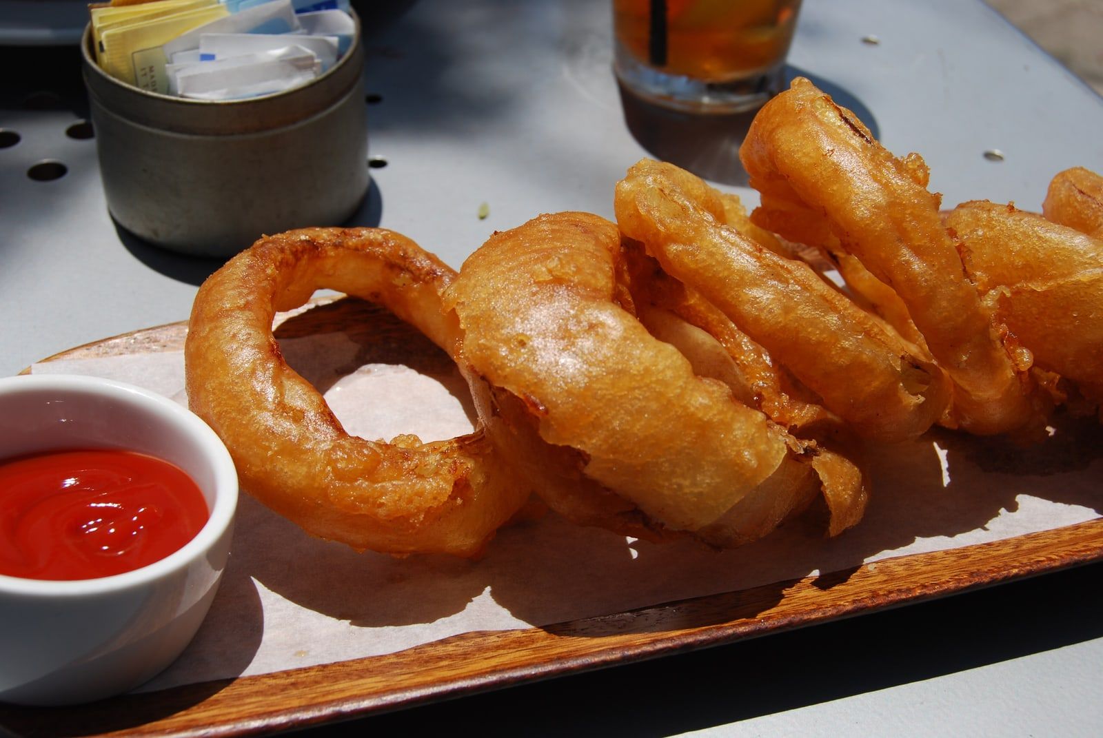 Aros de cebolla rebozados con un pote de ketchup