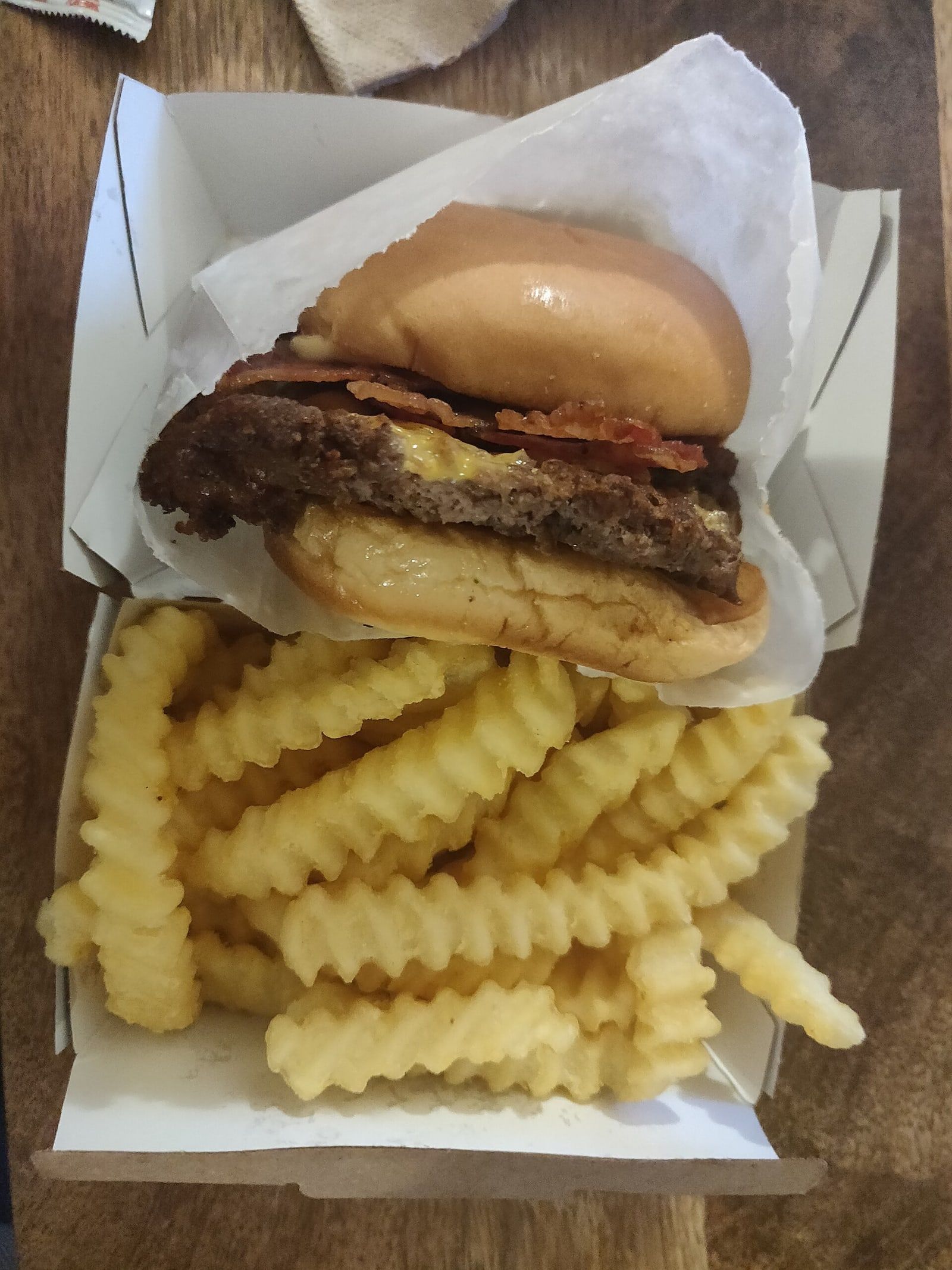 Hamburguesa de doble medallón con cheddar fundido, servida sobre papas