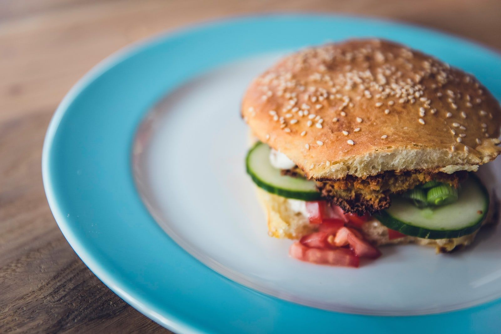 Hamburguesa vegetariana con pepino y tomate en un plato celeste